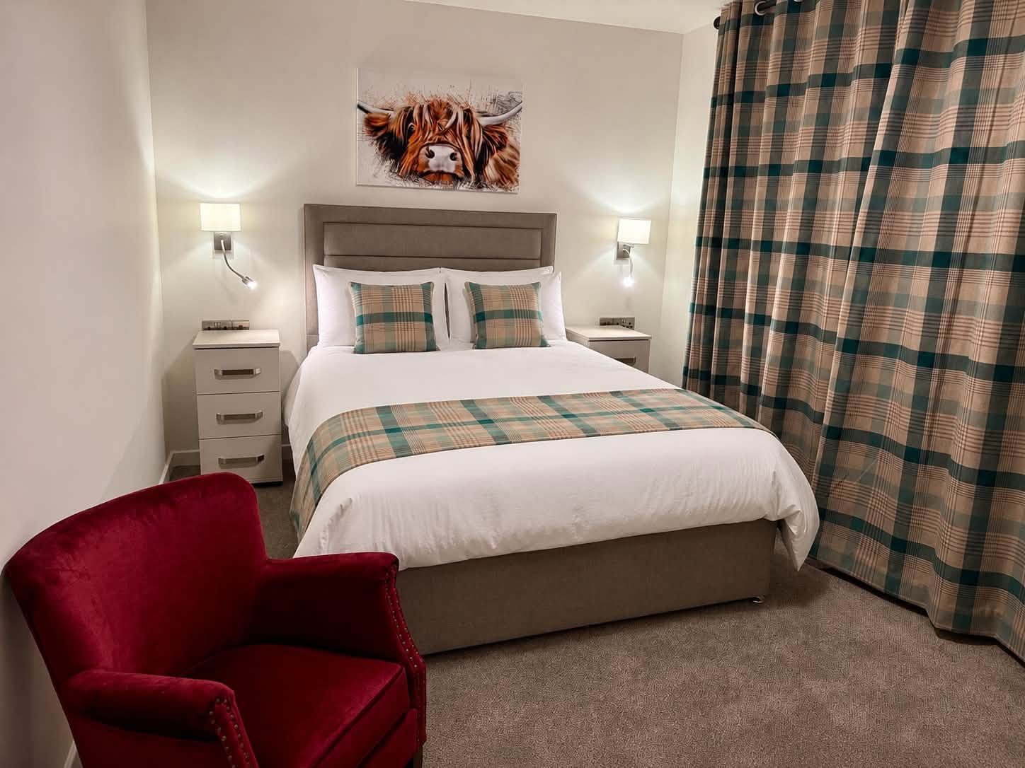 Furnished bedroom with grey headboard, teal tartan cushions and Highland cow artwork