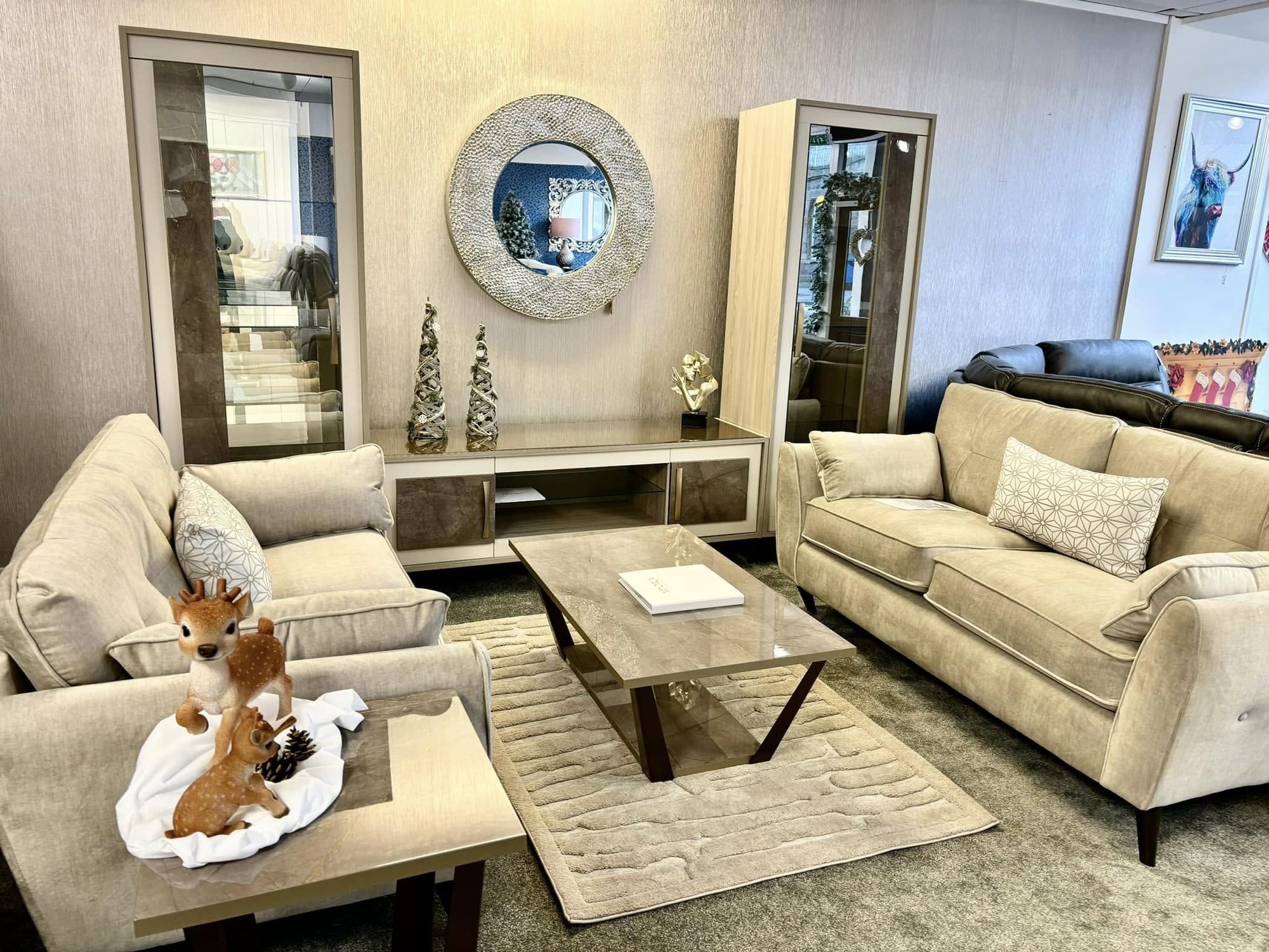 Furnished living room setting with beige sofas, stone-top tables and large decorative mirrors