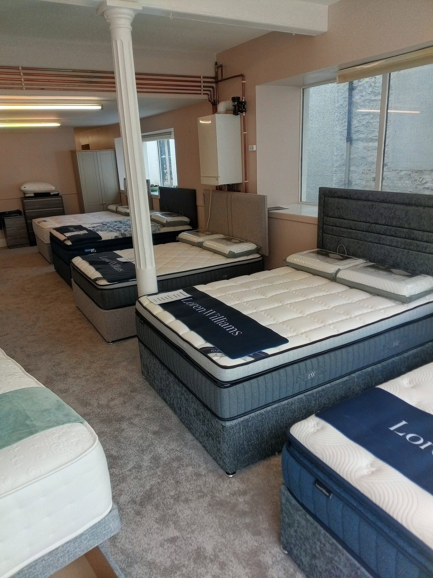 Row of Loren Williams divan beds and upholstered headboards in the Keith bed showroom