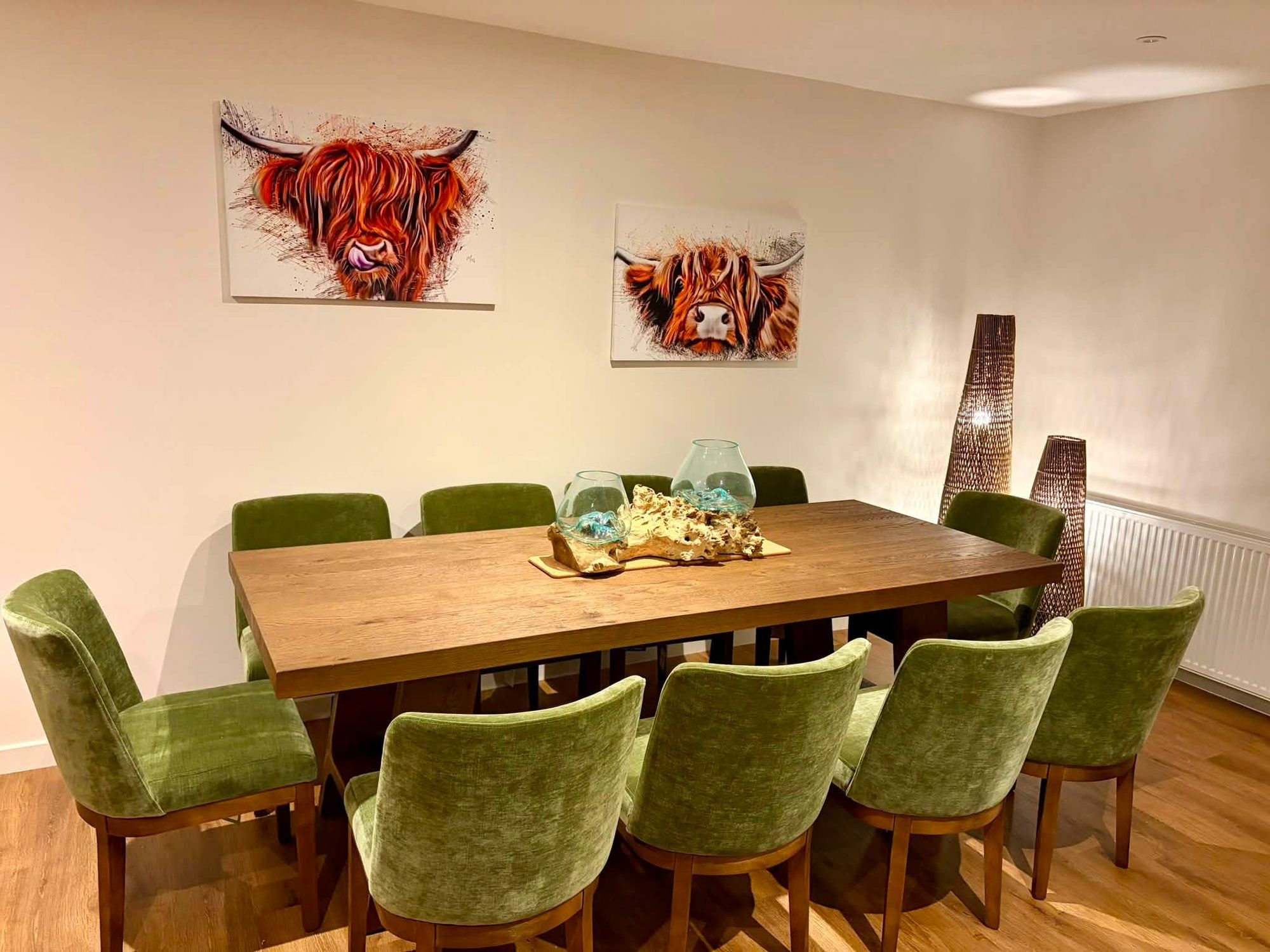 Dining room furnished with a large wooden table and eight green velvet dining chairs