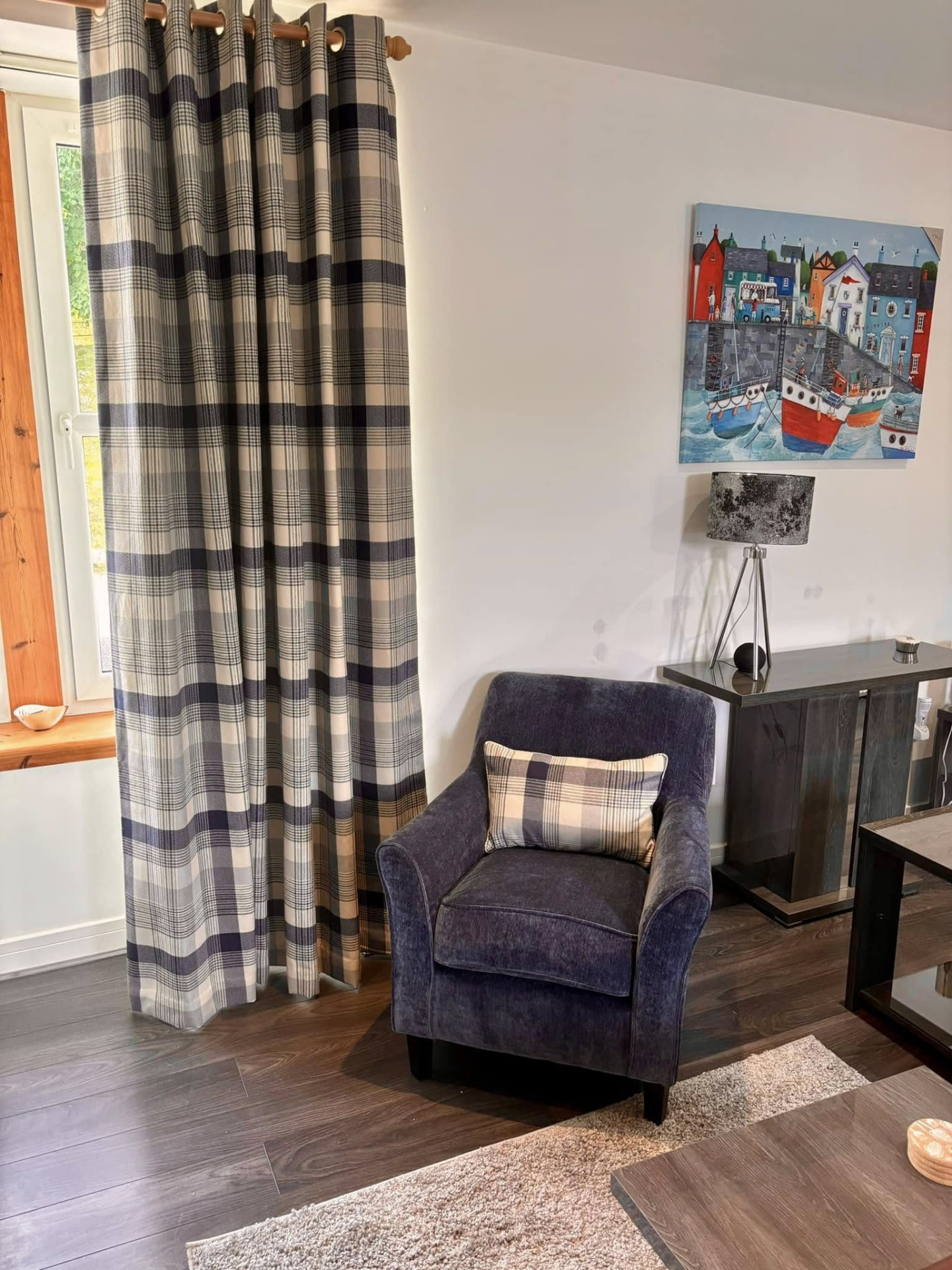 Blue and beige tartan curtains with a matching blue upholstered armchair in a lounge