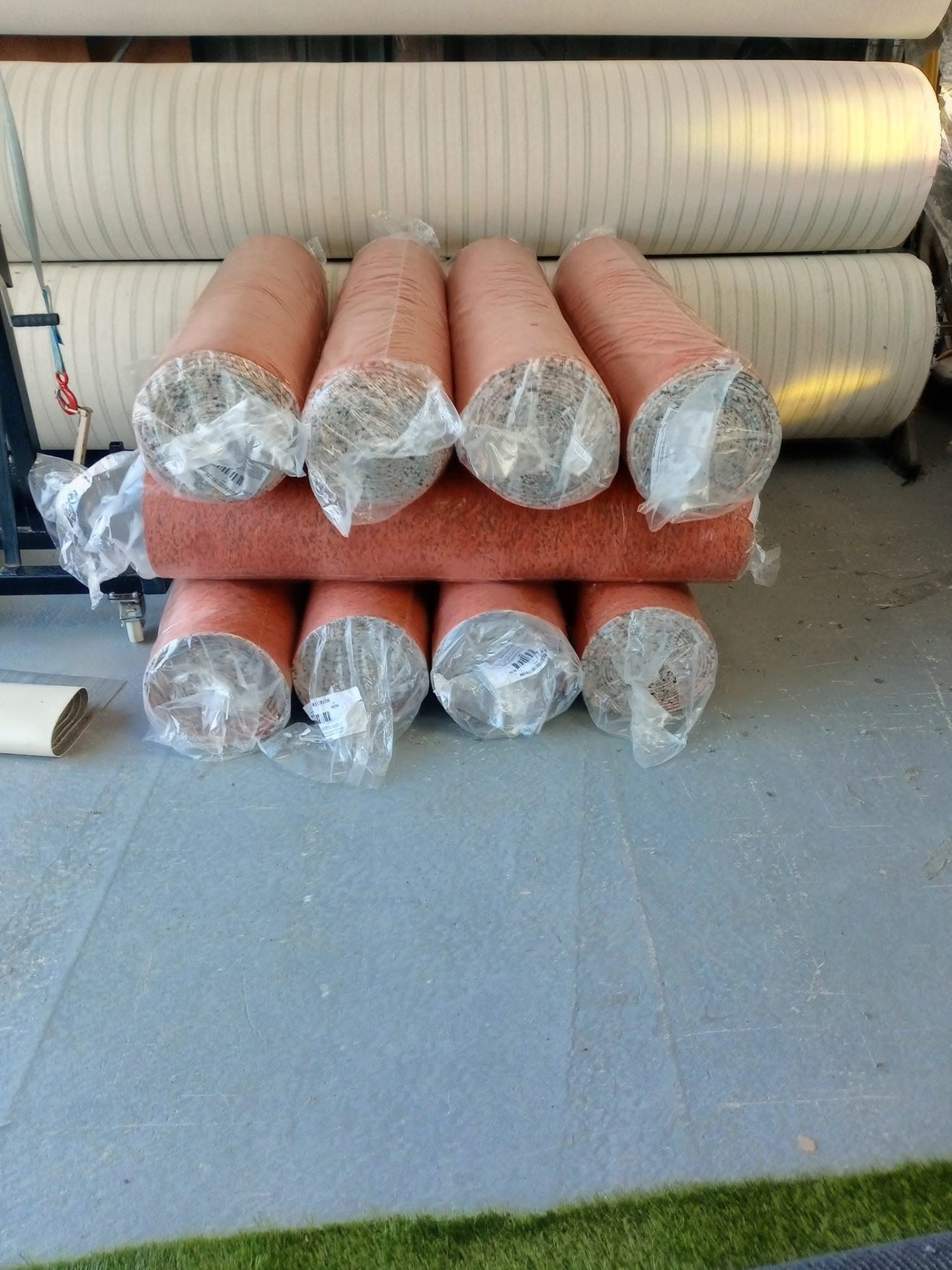 Wrapped carpet rolls in stock, including warm orange tones, ready for fitting across Moray