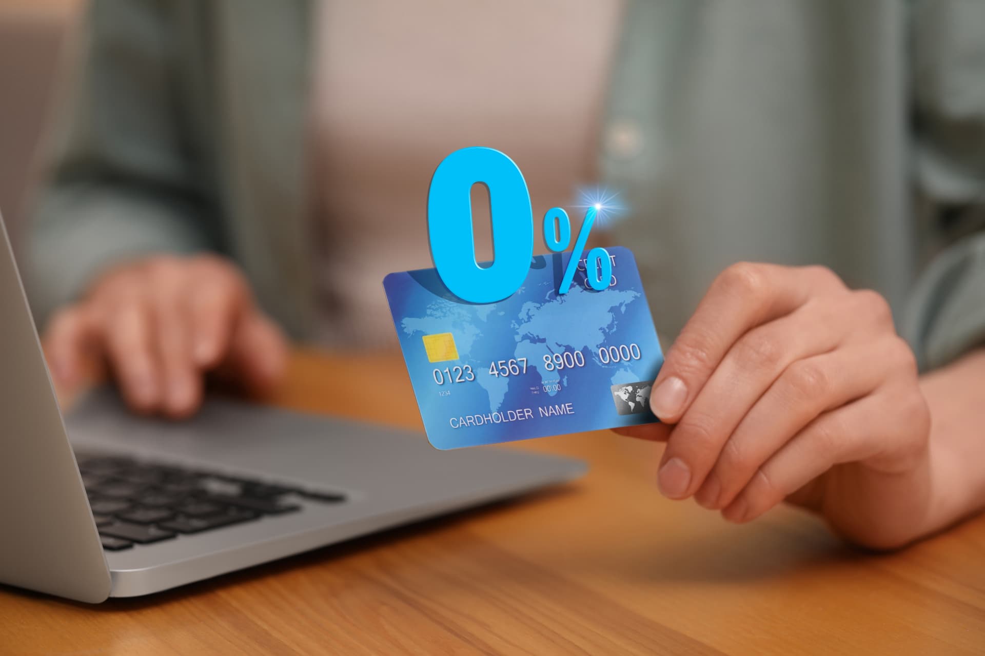 Customer holding a credit card beside a laptop with a 0% interest symbol