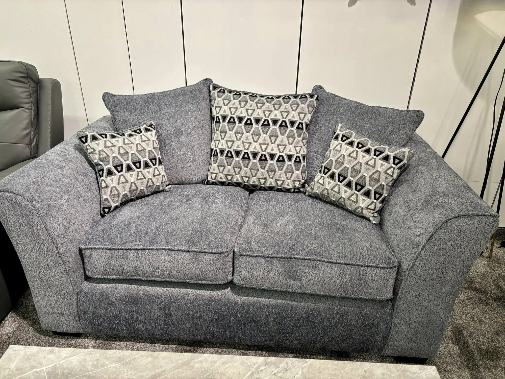 Grey fabric loveseat with large patterned scatter cushions