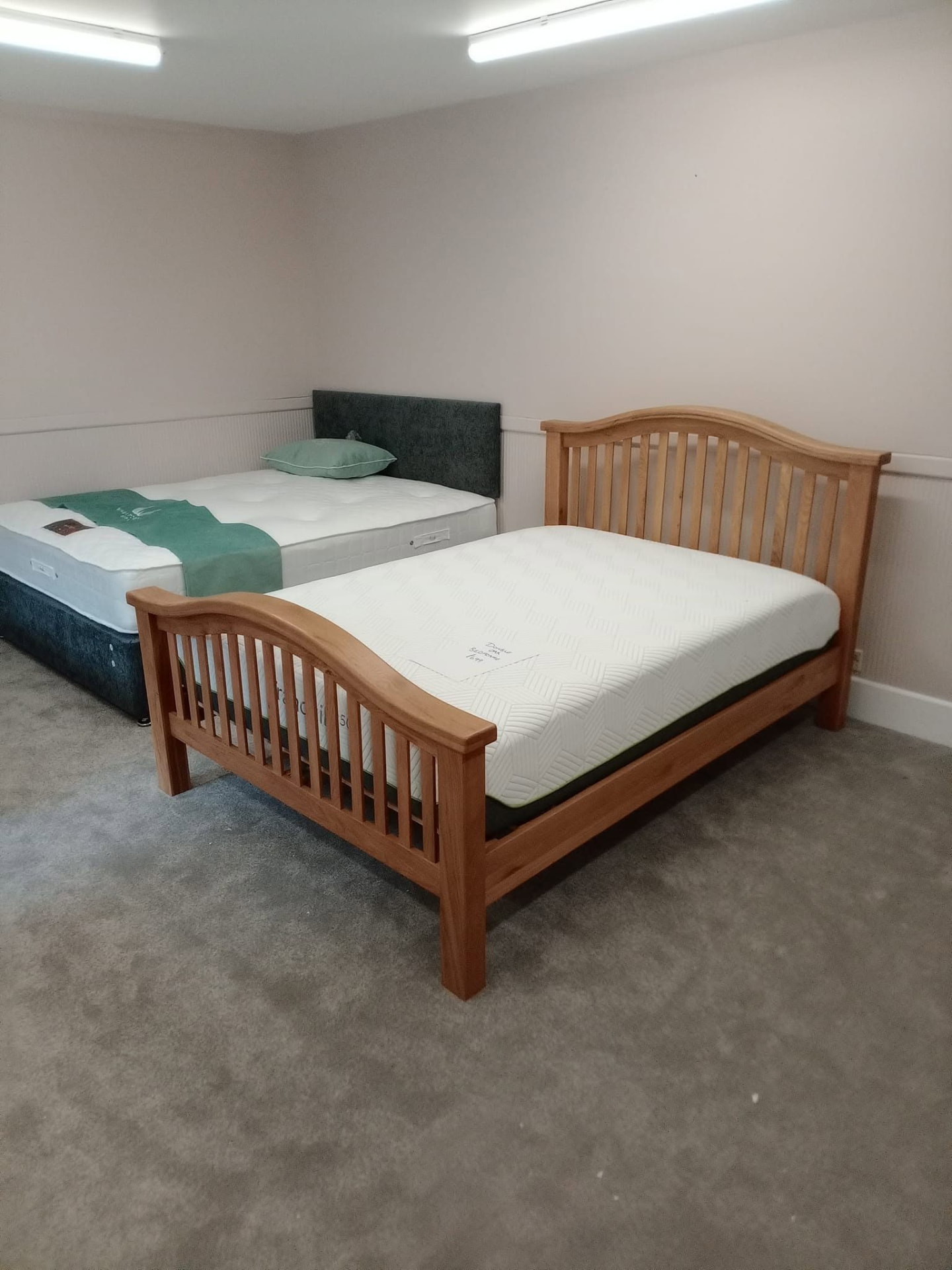 Oak slatted bed frame and grey fabric headboard bed on display in the Taylor's of Keith bed showroom